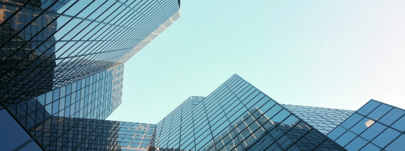 An upward shot of glass skyscrapers against a bright blue sky.