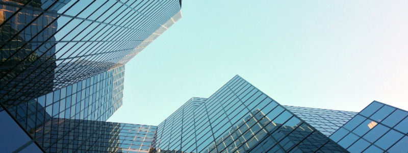 An upward view of multiple tall glass buildings, representing corporate offices and business.