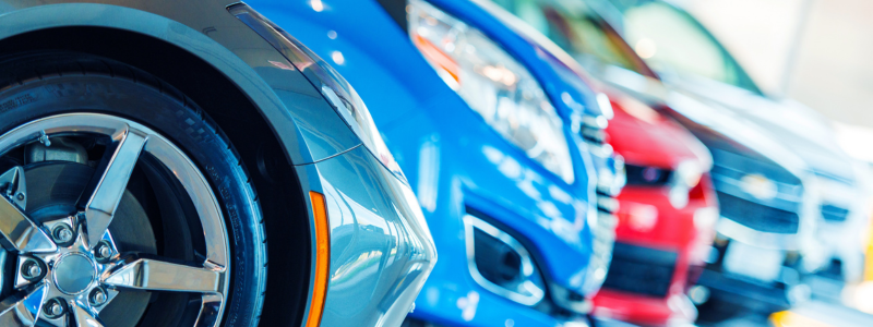 A row of the front of cars, all in different colours and models.