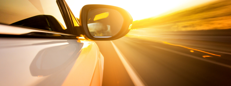 A close up of the side of a car moving on a road, creating a blur effect.