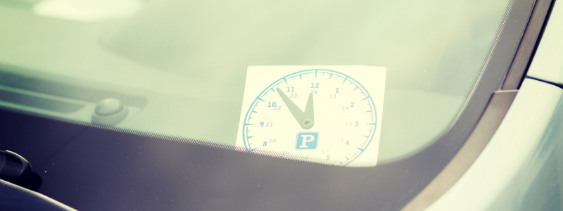 A close up of a clock sticker in a car, representing car waiting times.