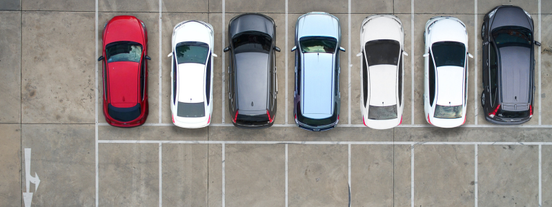 An overhead view of parking spaces, with cars in some and others empty.