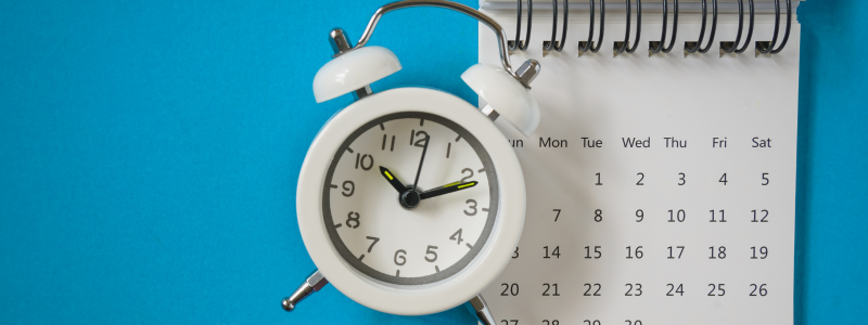 An alarm clock next to a calendar, representing payment dates.