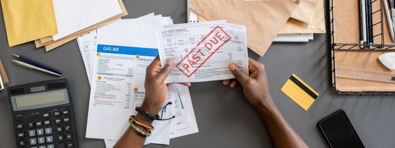 An overhead shot of someone looking through overdue bills, representing financial struggle.