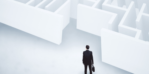 A business person stood at the entrance of a maze, representing business issues and challenges.