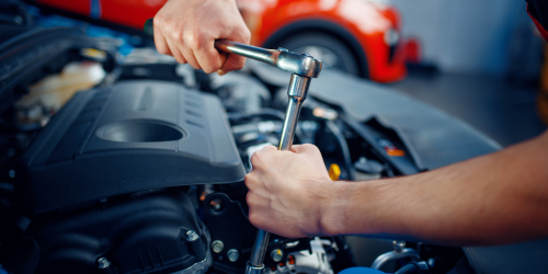 A close up of someone working on a car engine, likely as part of a car service.