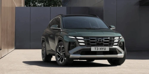 A green Hyundai Tucson parked in front of a futuristic building.