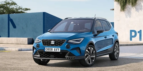 A blue Seat Arona in front of concrete blocks.