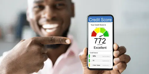 A person smiling holding up a phone that displays an excellent credit score.